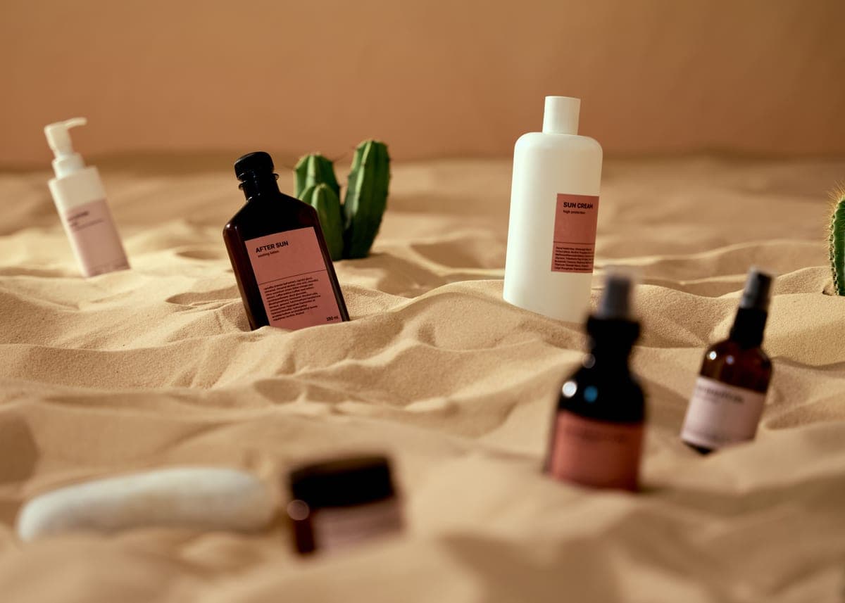 Kids and adult sunscreen bottles standing side by side on a towel