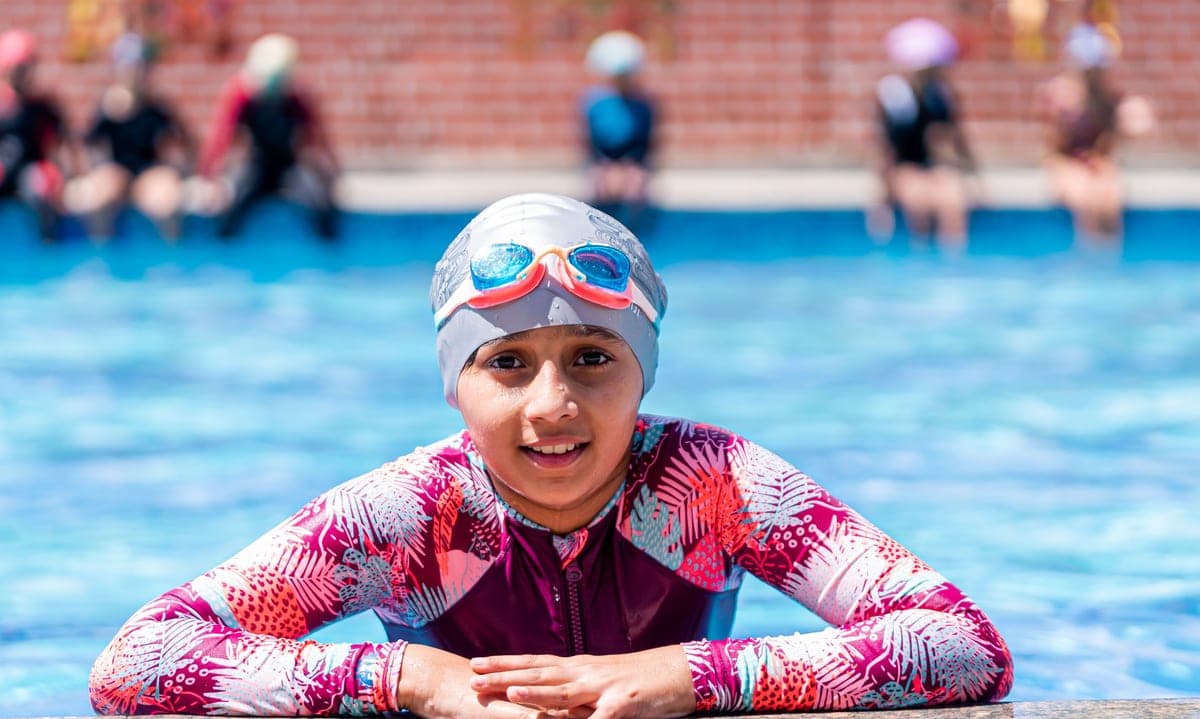 Parent reapplying sunscreen to a child between swims
