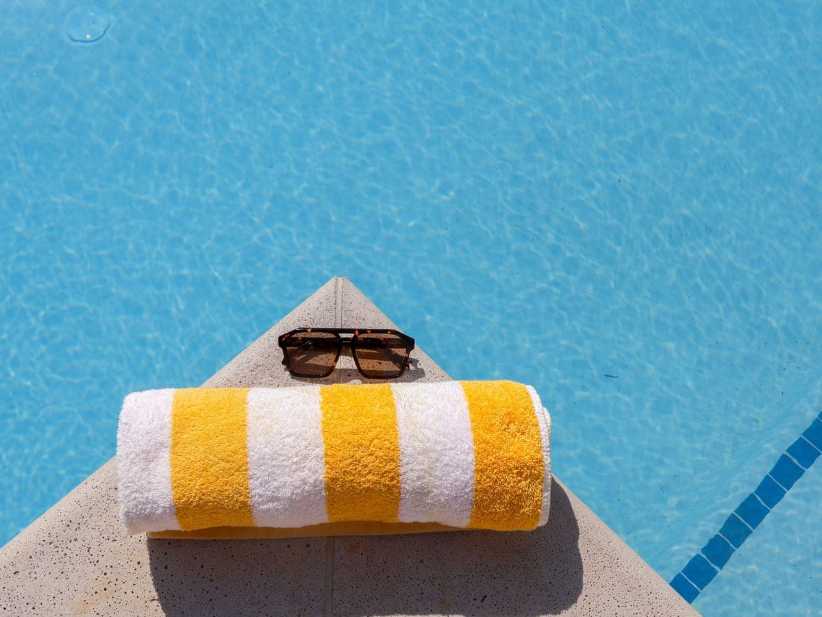 Mineral sunscreen bottles arranged on a sunlit poolside ledge