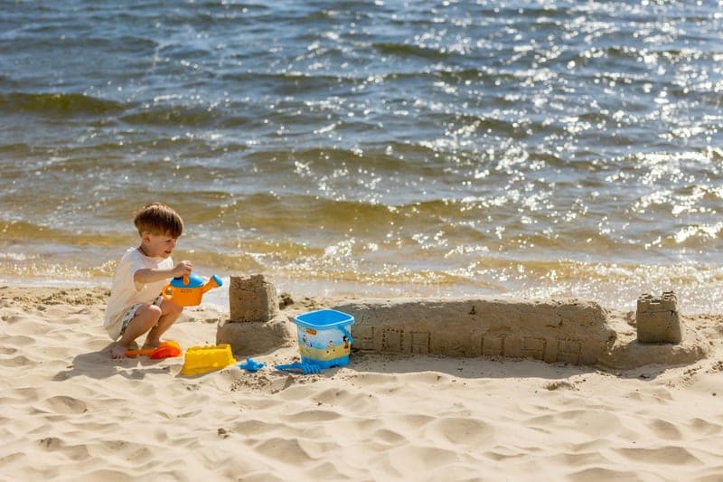 Mineral baby sunscreen beside a sun hat on sand