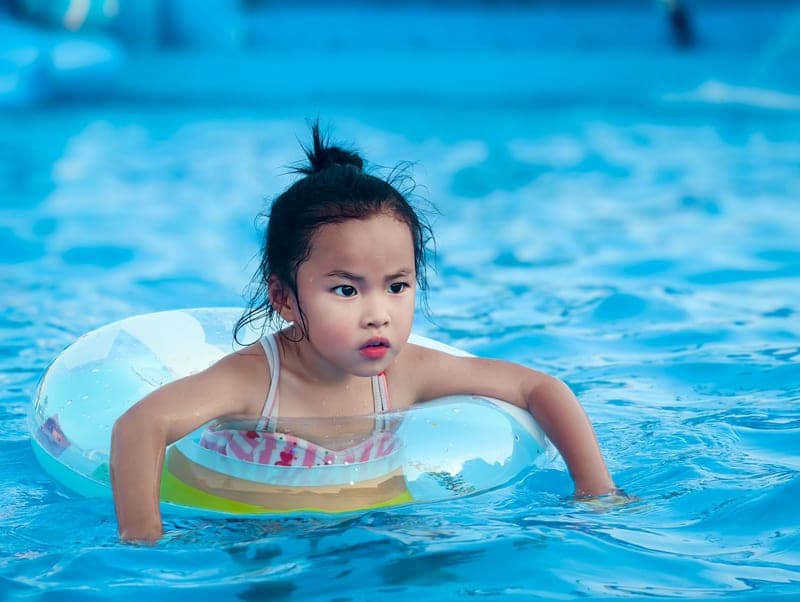 Child in a hooded rash guard at the shoreline