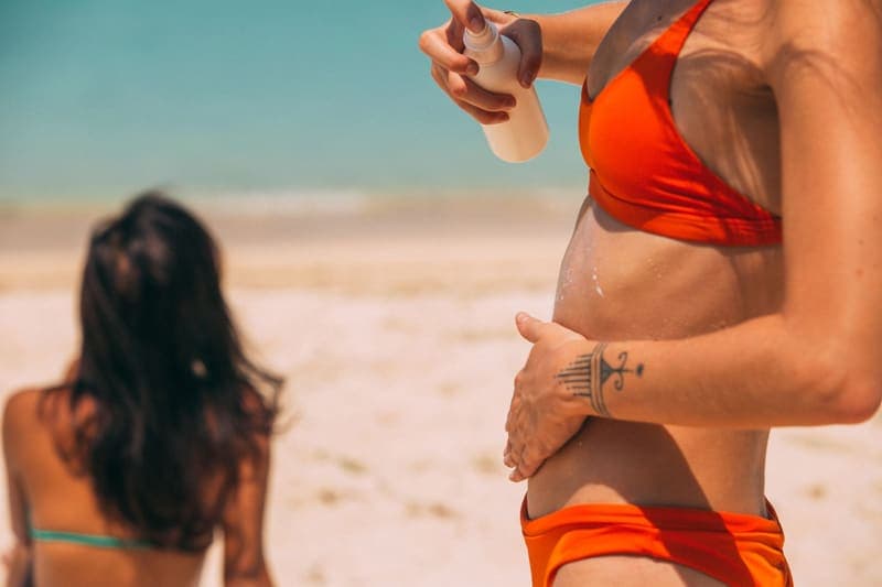 Spray sunscreen held up against a bright, open beach